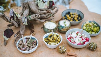 Assorted appetizers displayed on a rustic wooden table outdoors, perfect for a festive gathering.